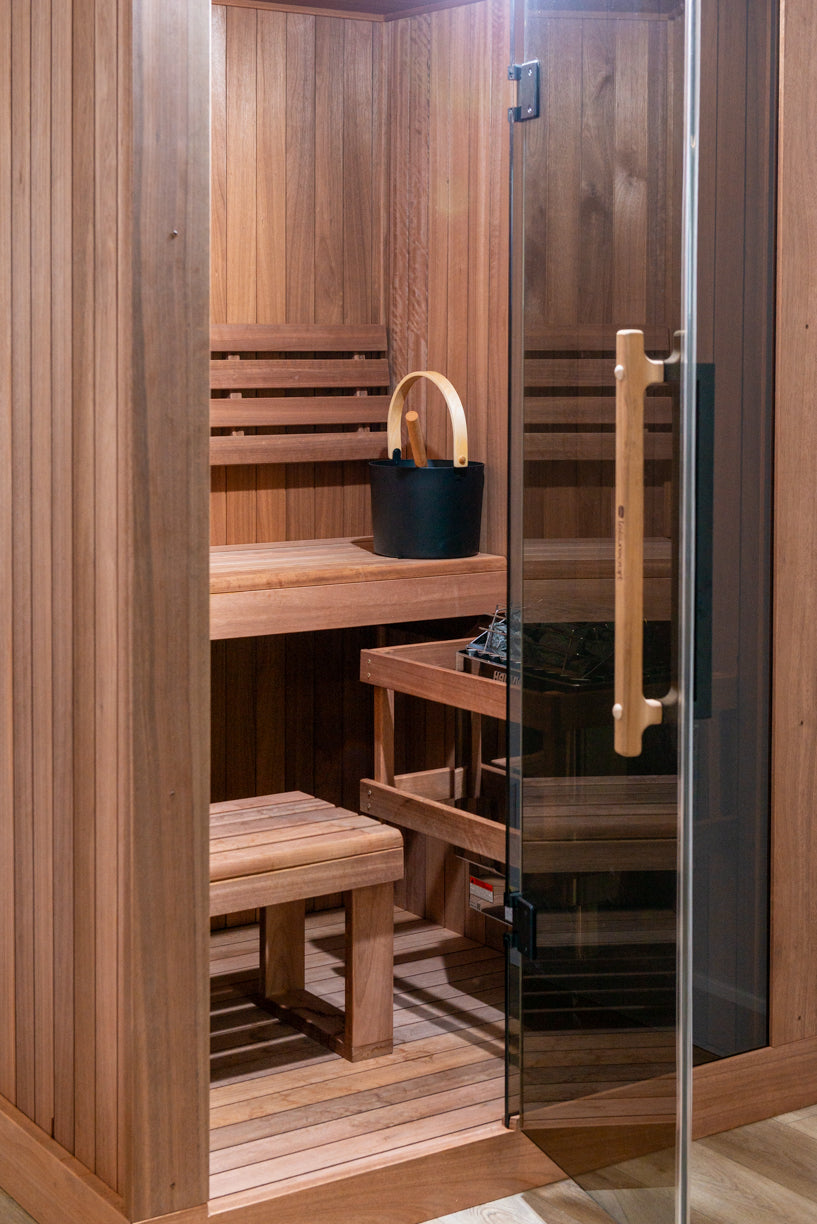Narrow interior of the Dundalk Leisurecraft Element Nook 1-2 Person Traditional Indoor Sauna seen through the glass door