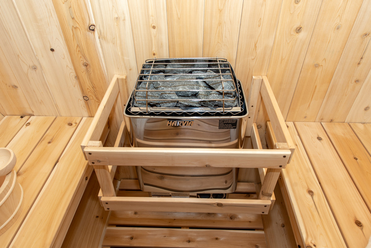 Heater with stones and safety rail inside the Dundalk CT Harmony 4-Person Outdoor Barrel Sauna