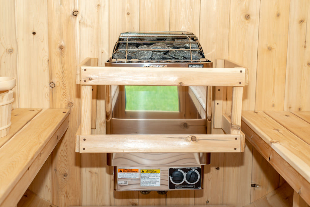Heater with stones and safety rail inside the Dundalk CT Harmony 4-Person Outdoor Barrel Sauna, close-up