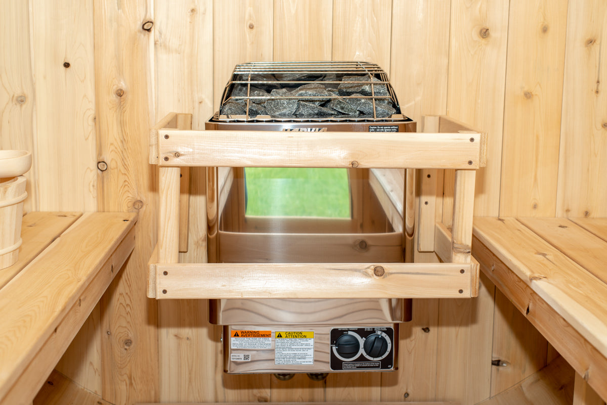 Heater with stones and safety rail inside the Dundalk CT Harmony 4-Person Outdoor Barrel Sauna, close-up