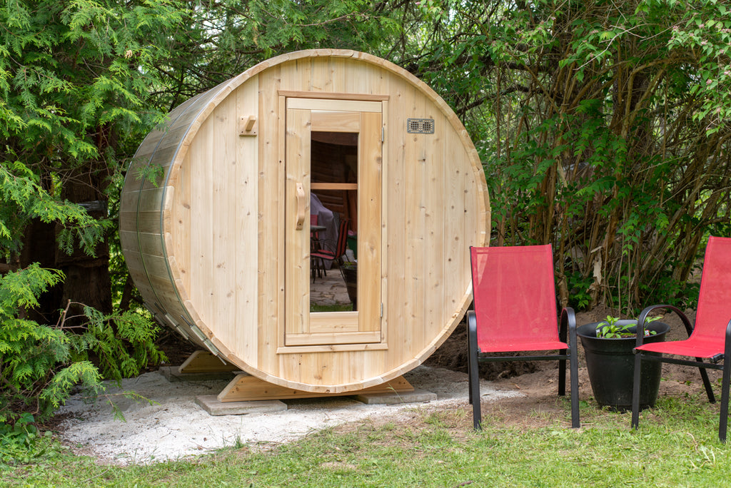Dundalk CT Harmony 4-Person Outdoor Barrel Sauna with patio chairs in a garden