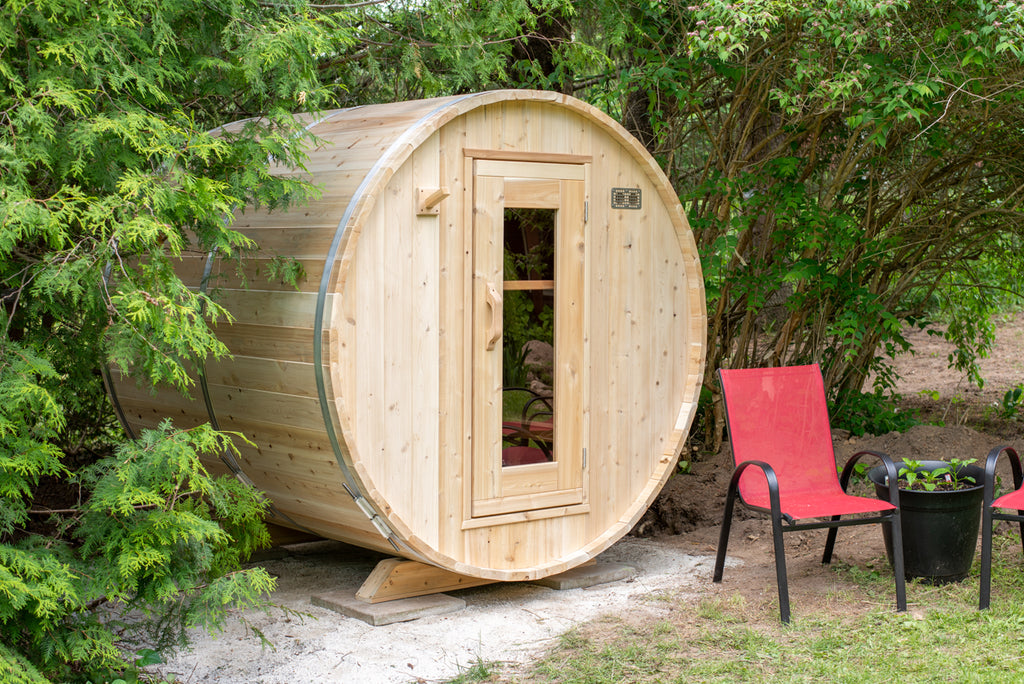 Dundalk CT Harmony 4-Person Outdoor Barrel Sauna beside red patio chairs