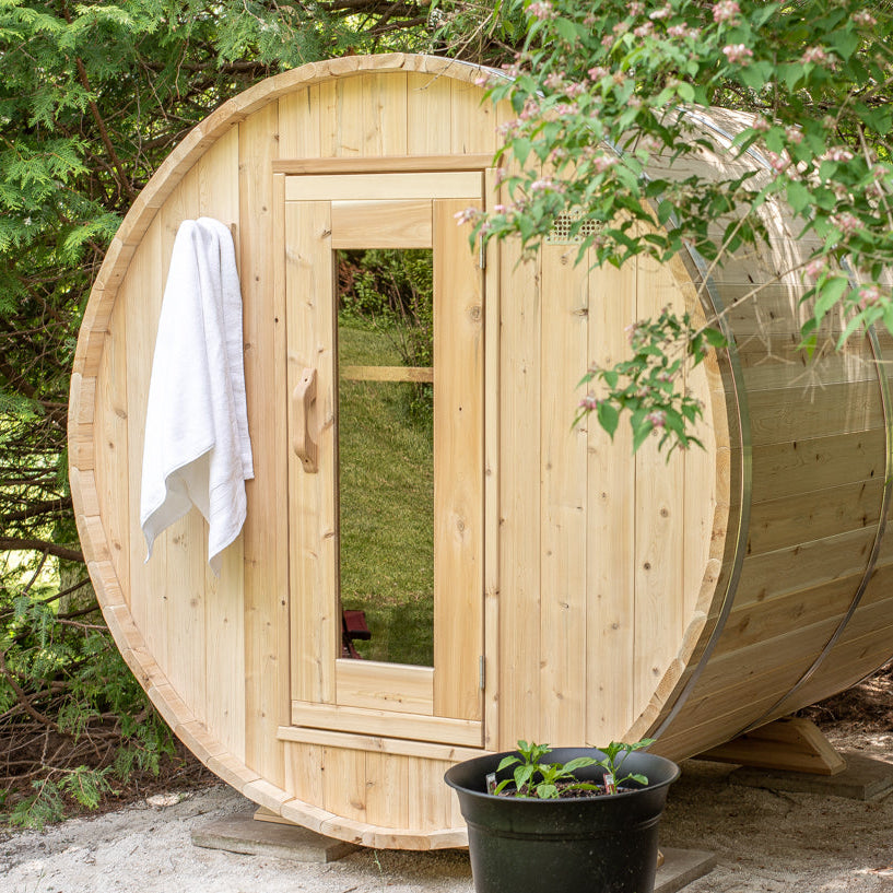 Front view of the Dundalk CT Harmony 4-Person Outdoor Barrel Sauna with towel hanging by the door