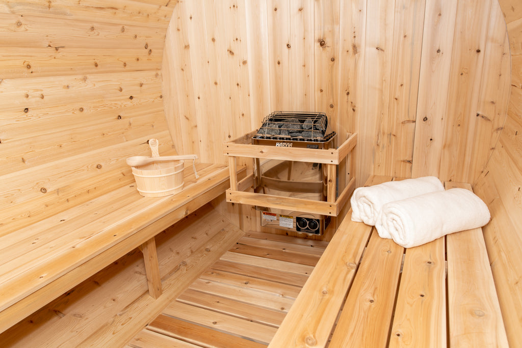 Heater with stone rack and benches inside the Dundalk CT Tranquility 6-Person Outdoor Barrel Sauna