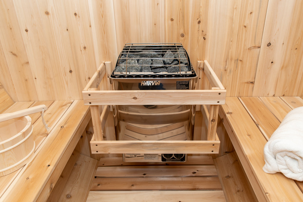 Heater with stone rack and safety rail inside the Dundalk CT Tranquility 6-Person Outdoor Barrel Sauna