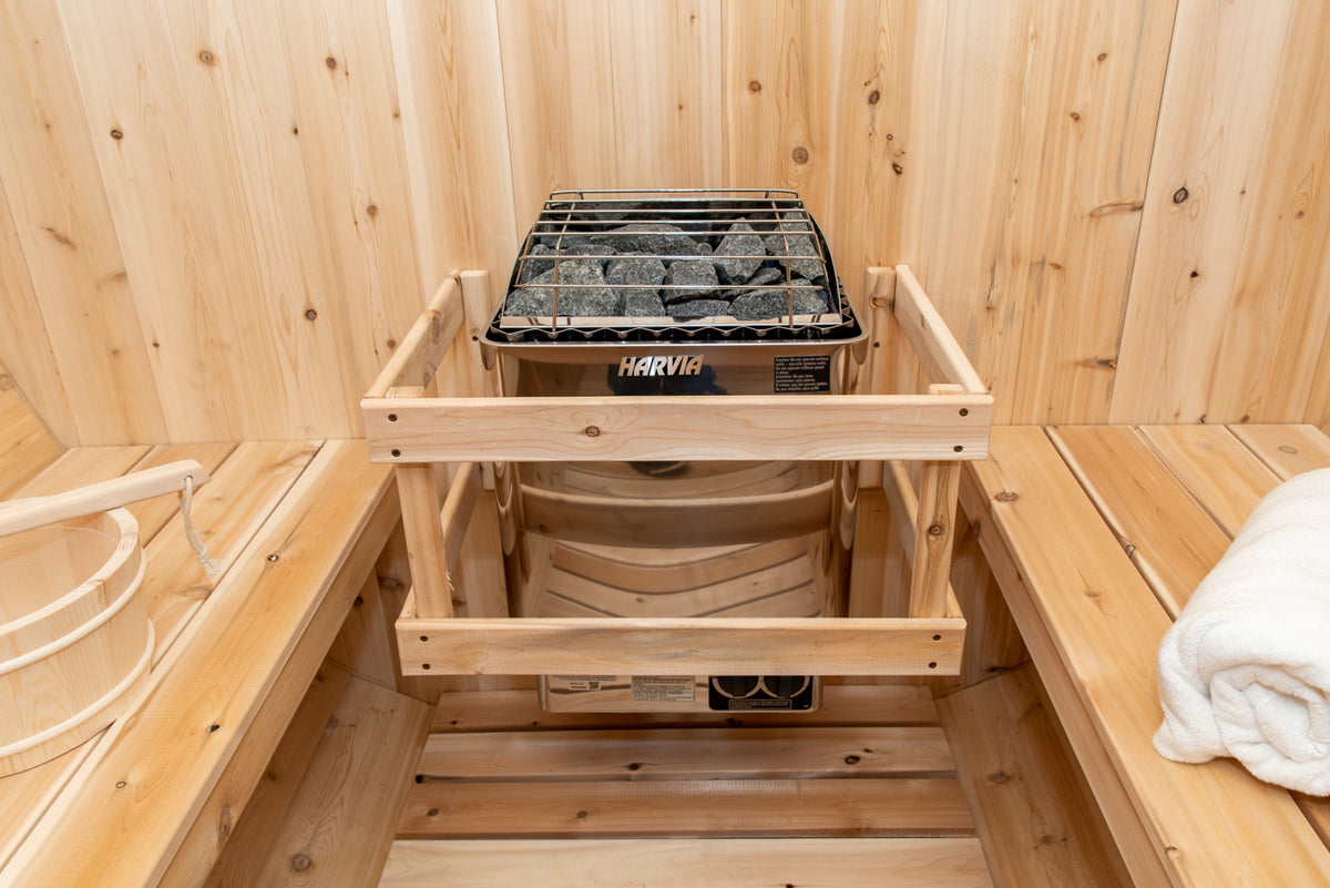 Heater with stone rack and safety rail inside the Dundalk CT Tranquility 6-Person Outdoor Barrel Sauna