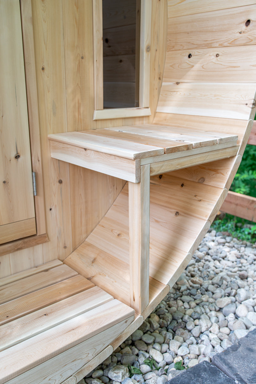 Porch bench and door of the Dundalk CT Tranquility 6-Person Outdoor Barrel Sauna