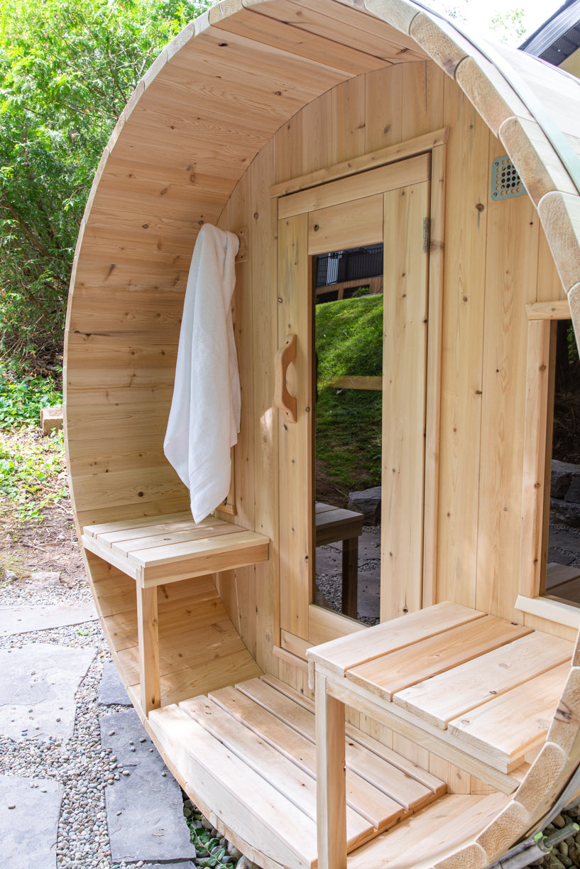 Front door and porch bench of the Dundalk CT Tranquility 6-Person Outdoor Barrel Sauna