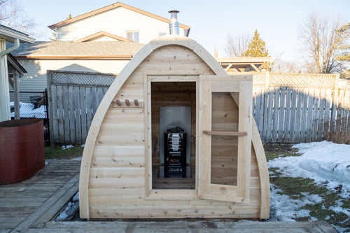 Front view of the Dundalk CT MiniPOD 4-Person Sauna with door and window in a backyard