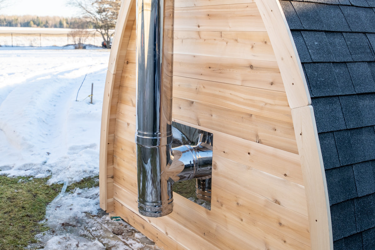 Side of the Dundalk CT MiniPOD 4-Person Sauna with stove chimney pipe in snow