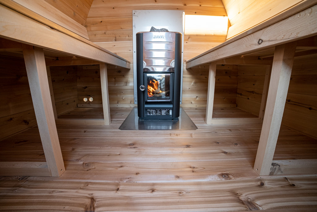 Wood stove at the end of the benches inside the Dundalk CT MiniPOD 4-Person Sauna