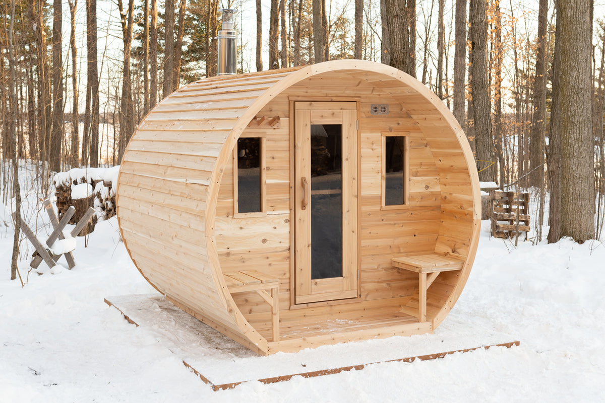 Dundalk CT Elation 4-Person Outdoor Barrel Sauna with front window and porch bench in winter
