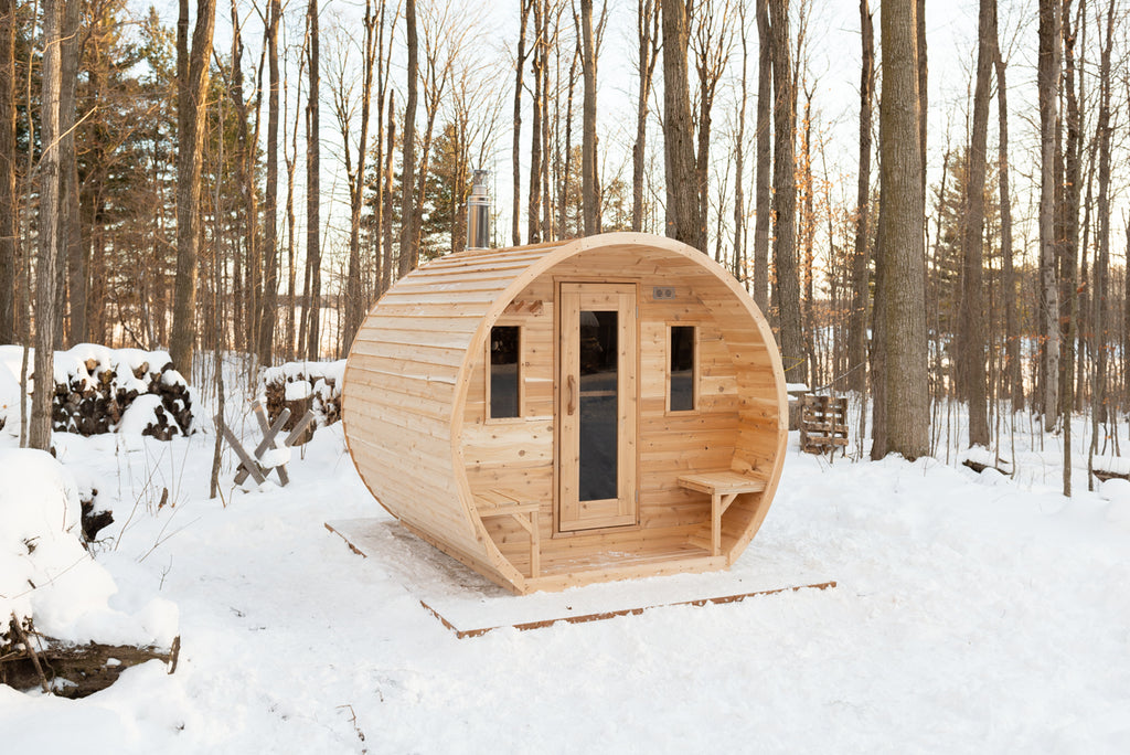 Front view of the Dundalk CT Elation 4-Person Outdoor Barrel Sauna in a snowy forest