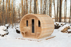 Angled front view of the Dundalk CT Elation 4-Person Outdoor Barrel Sauna in a snowy forest