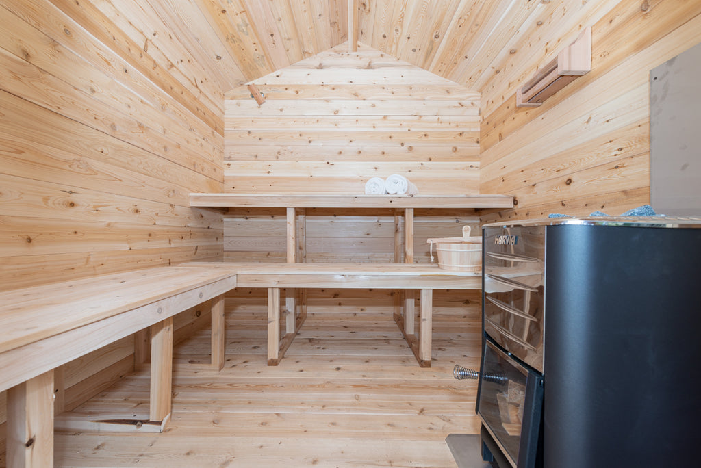 Interior of the Dundalk CT Georgian 6-Person Outdoor Cabin Sauna with benches and black heater
