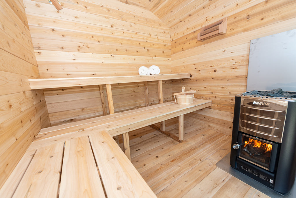 Benches and wood-burning stove inside the Dundalk CT Georgian 6-Person Outdoor Cabin Sauna