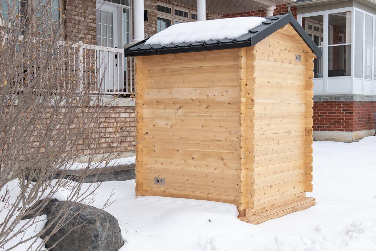 Rear angled view of the Dundalk CT Granby 3-Person Outdoor Cabin Sauna in the snow