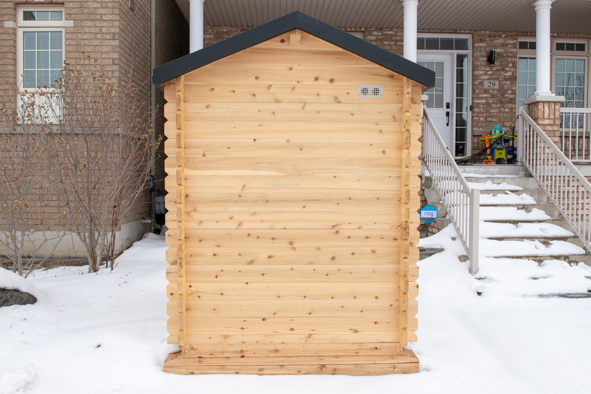 Rear view of the Dundalk CT Granby 3-Person Outdoor Cabin Sauna beside a house