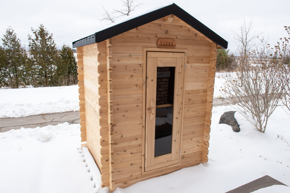 Angled front view of the Dundalk CT Granby 3-Person Outdoor Cabin Sauna in the snow