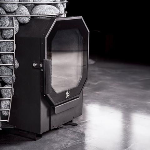Angled view of the glass fire door on the Huum Hive Flow 9.8kW wood-burning sauna stove