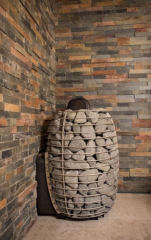 Huum Hive Wood LS 17kW wood-burning sauna stove with sauna stones installed in a sauna corner