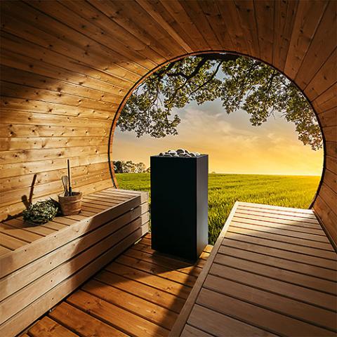 Huum Core 6.5kW Sauna Heater in a barrel sauna with round window and garden view