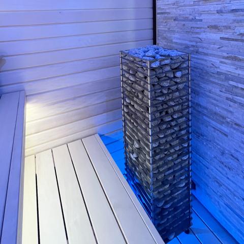 Huum Cliff 10.5kW Sauna Heater in a sauna with blue lighting and white benches