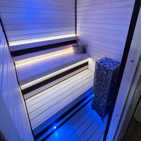 Huum Cliff 10.5kW Sauna Heater in a sauna with blue lighting and white benches, alternate view