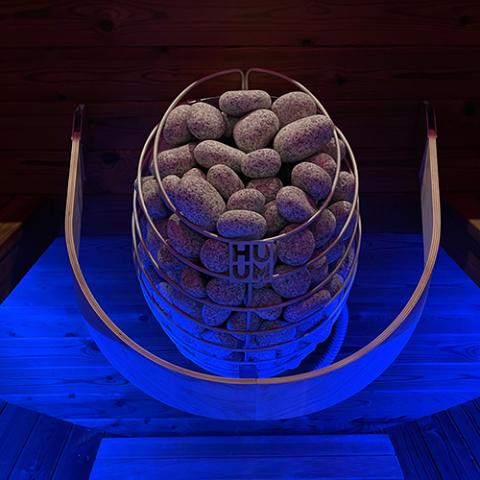 Huum Drop 4.5kW Sauna Heater in a sauna with blue accent lighting
