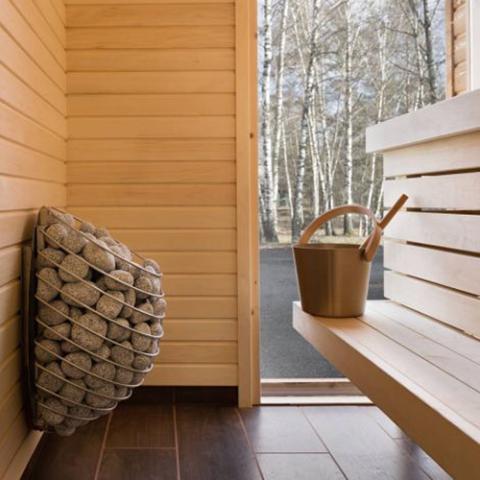 Huum Drop 7.5kW Sauna Heater wall-mounted beside a bucket and window in a sauna