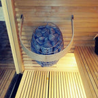 Huum Drop 6kW Sauna Heater in a sauna with safety rail and warm lighting