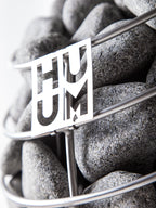 Close-up of the Huum logo on the stone cage of the Huum Drop 6kW Sauna Heater