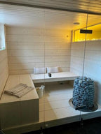 Huum Hive 18kW Sauna Heater in a sauna with white benches
