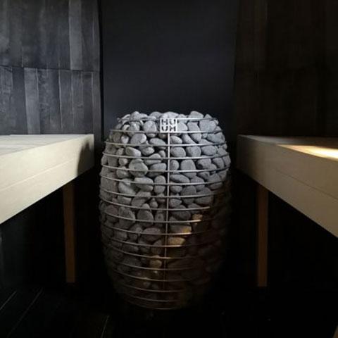 Huum Hive 18kW Sauna Heater in a dark-walled sauna