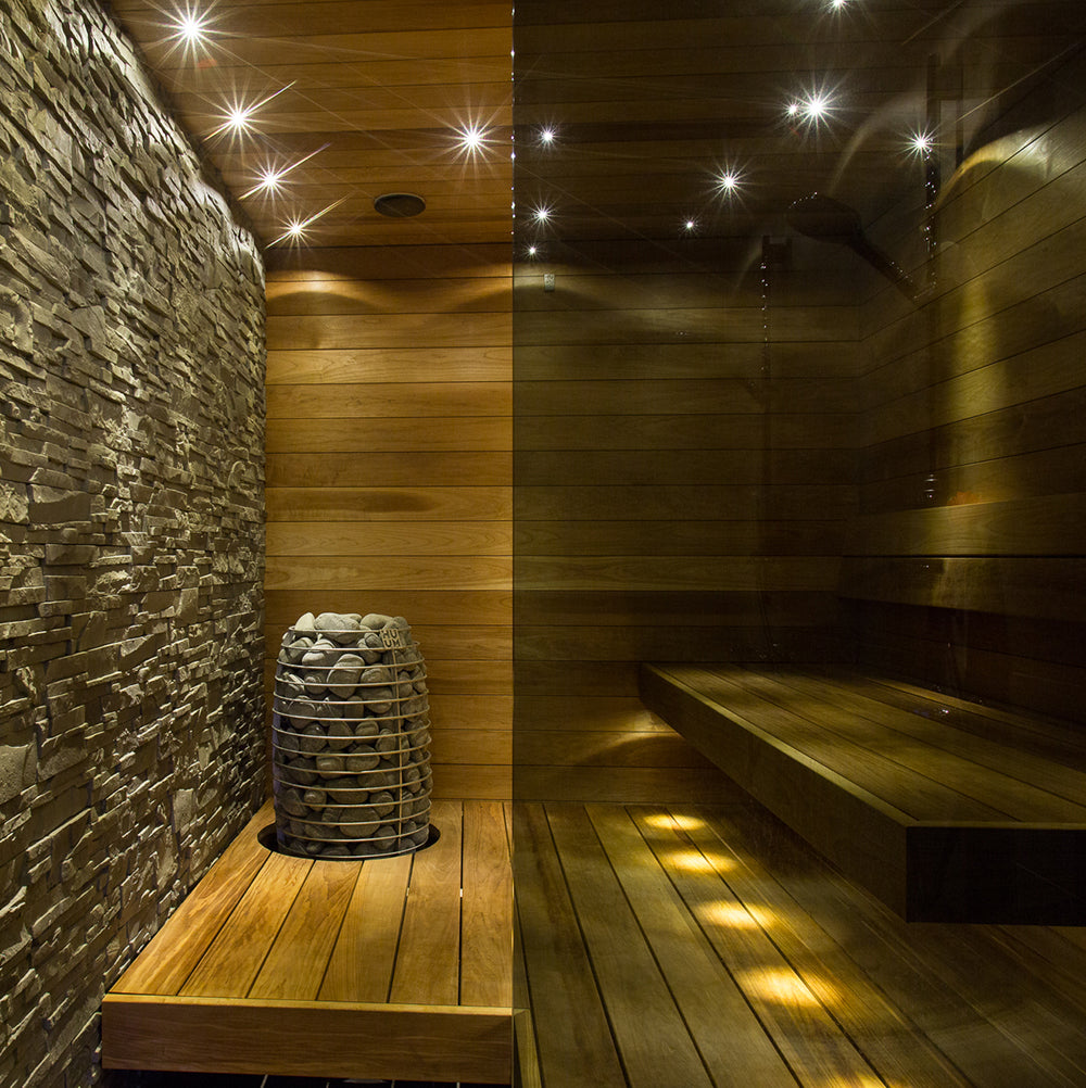 Huum Hive Mini 9kW Sauna Heater in a sauna with warm accent lighting and stone wall