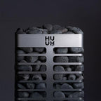Front view of the Huum Steel 10.5kW Sauna Heater with sauna stones on a dark background