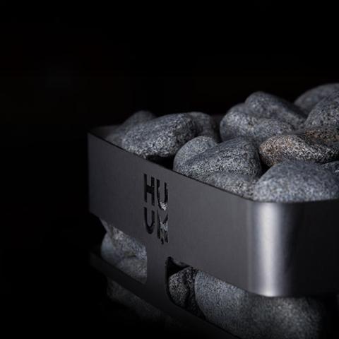 Close-up of the Huum logo and stone-filled top of the Huum Steel Mini 3.5kW Sauna Heater