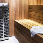 Huum Steel Mini 3.5kW Sauna Heater beside a sauna bench with folded towel