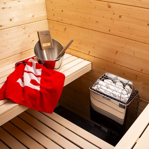 Harvia KIP 8kW electric sauna heater in a sauna with bucket and towel