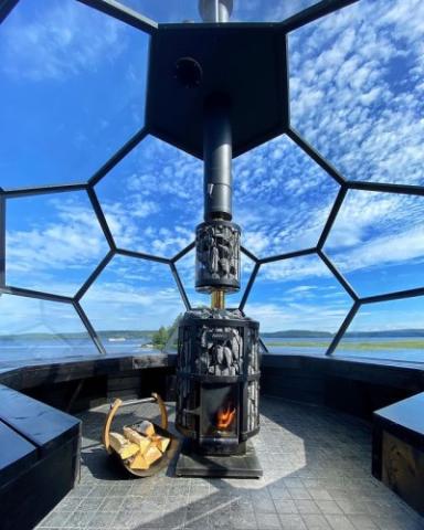 Harvia Legend 240 GreenFlame 15.9kW Wood-Burning Sauna Stove in a glass-dome sauna with a sky view