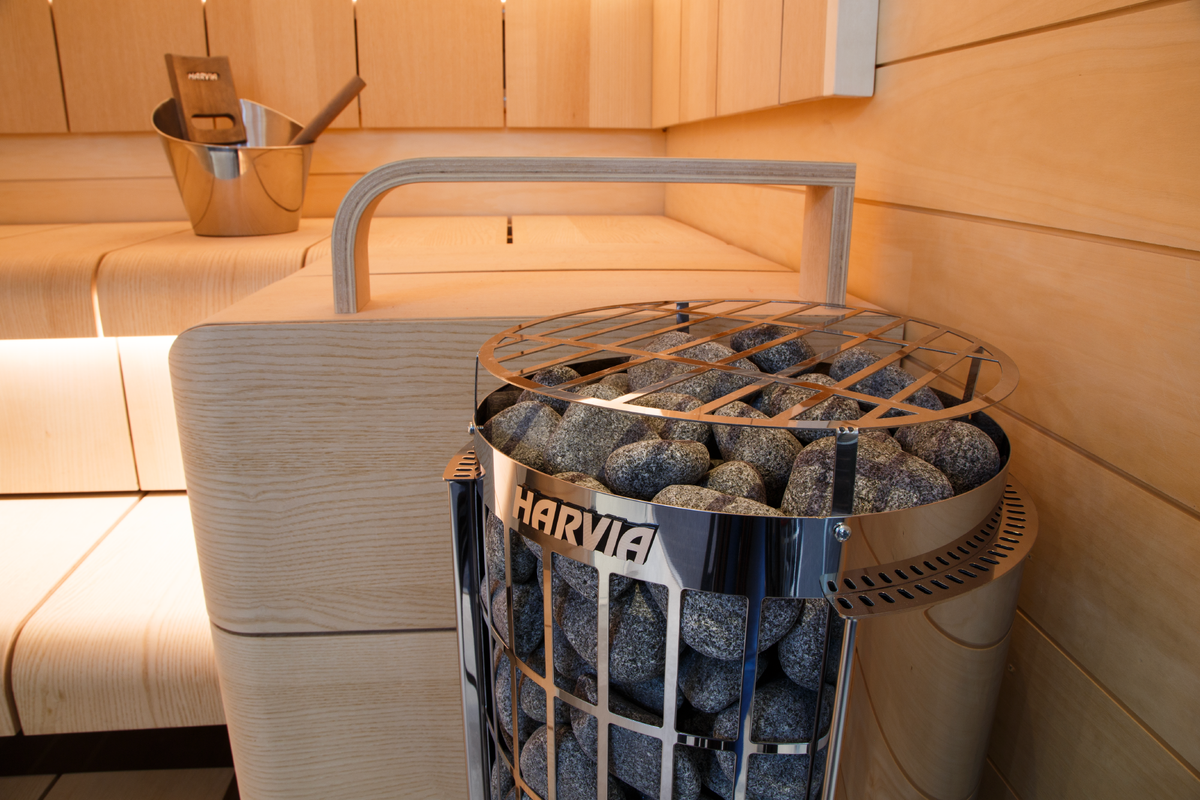 Harvia Cilindro PC80E 8kW electric sauna heater in a sauna with sauna stones and wooden benches