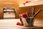 Sauna interior with bucket and towel next to the Harvia The Wall 6kW electric sauna heater