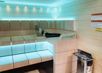 Harvia The Wall 6kW electric sauna heater in a sauna with cyan lighting and white benches