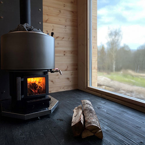 Narvi Luosto VS 16kW wood burning sauna stove with fire burning in a sauna with a large window