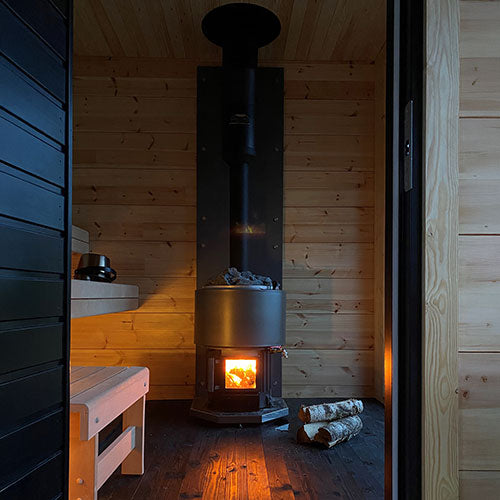 Narvi Luosto VS 16kW wood burning sauna stove with fire burning and a chimney in a wood-panelled sauna