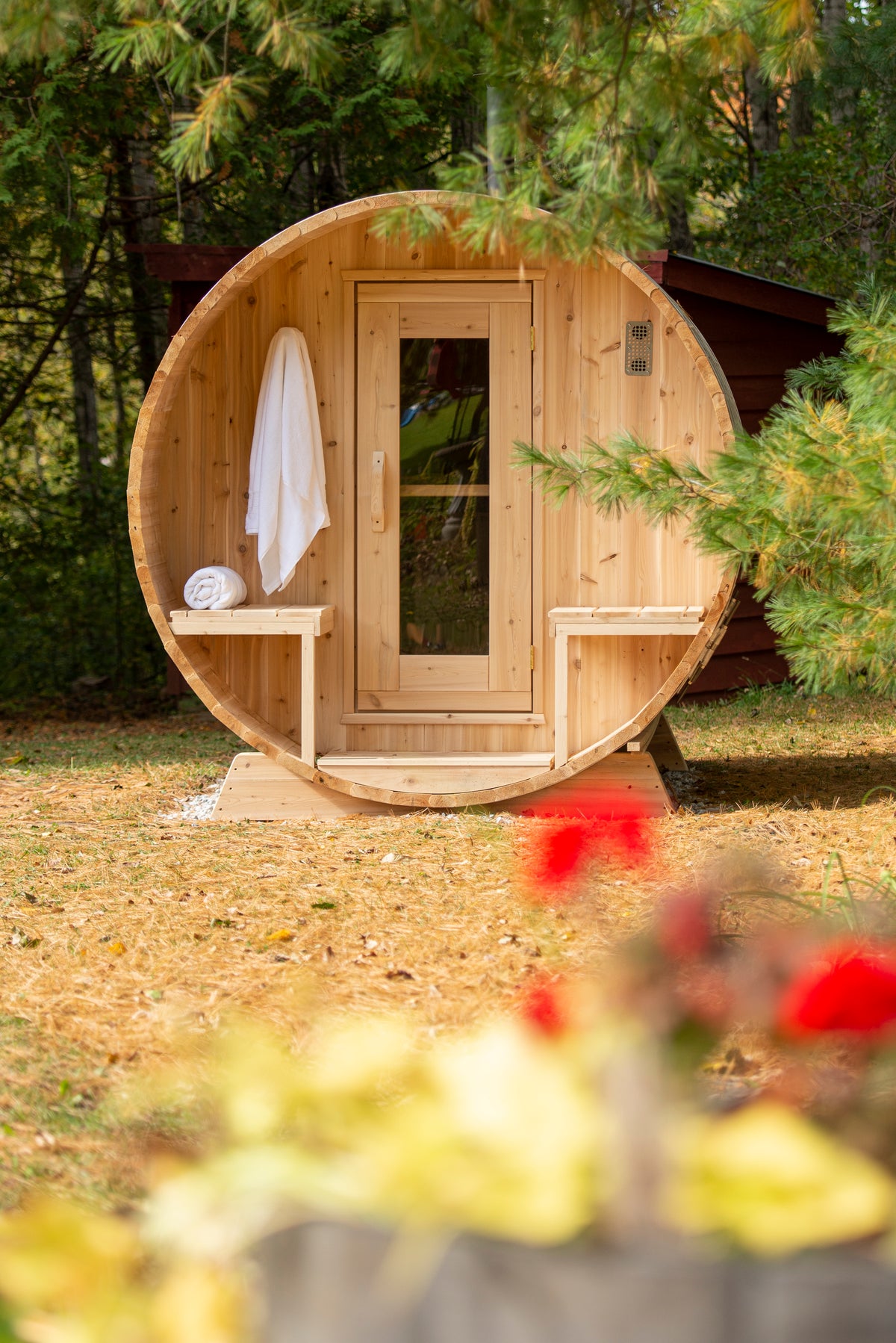 Front view of the Dundalk CT Serenity 5-Person Outdoor Barrel Sauna with towel hanging by the door