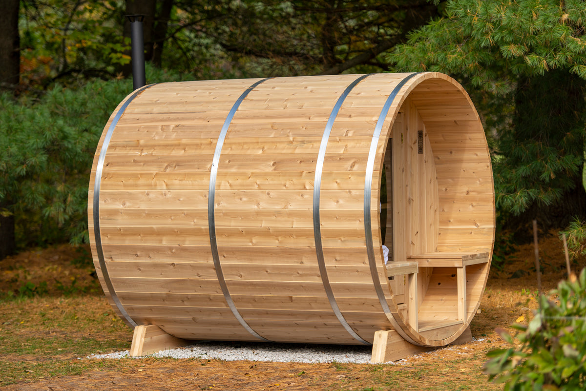 Side view of the Dundalk CT Serenity 5-Person Outdoor Barrel Sauna on a lawn beside trees