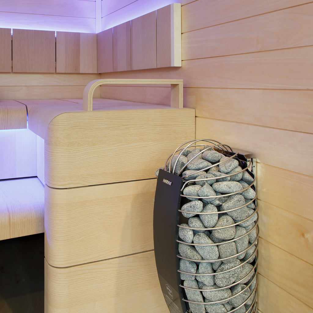 Harvia Spirit 6kW electric sauna heater mounted on a sauna wall beside the bench